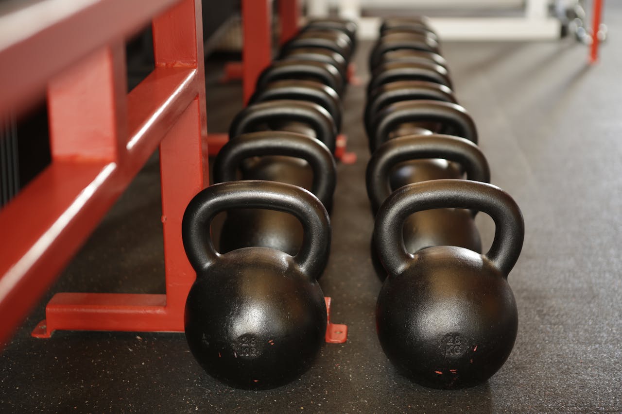 Black kettlebells lined up in a gym, ready for fitness training.