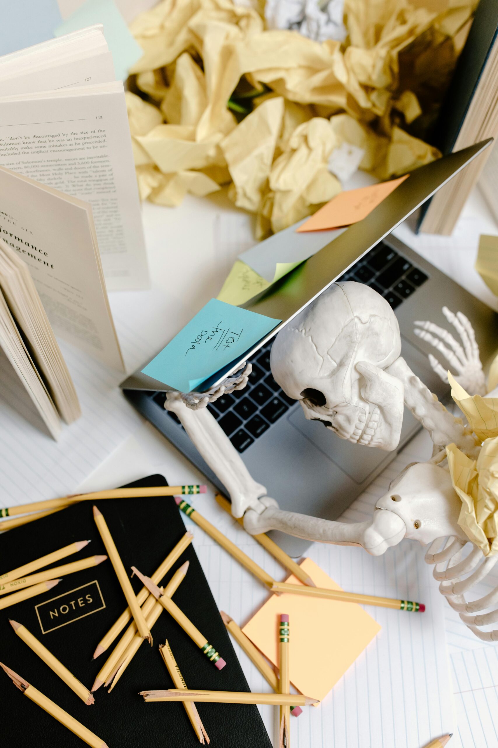 Skeleton at a desk overwhelmed with work symbolizing burnout, stress, and overworking.