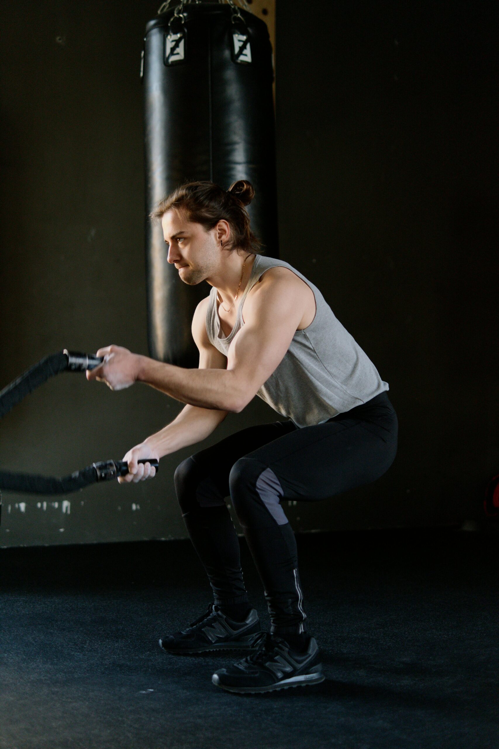 Athletic man doing intense battle rope workout inside a gym to build muscle and stamina.